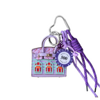 Lavender leather structured mini bag charm shaped like a house, featuring decorative window panels and a top handle.