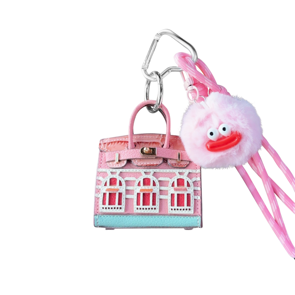 Pink leather structured mini bag charm shaped like a house, featuring decorative window panels and a top handle.