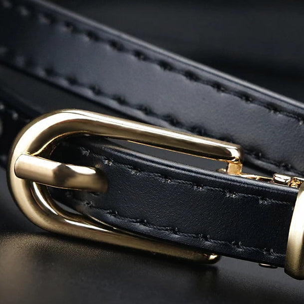 Black leather belt with a gold buckle on a dark background