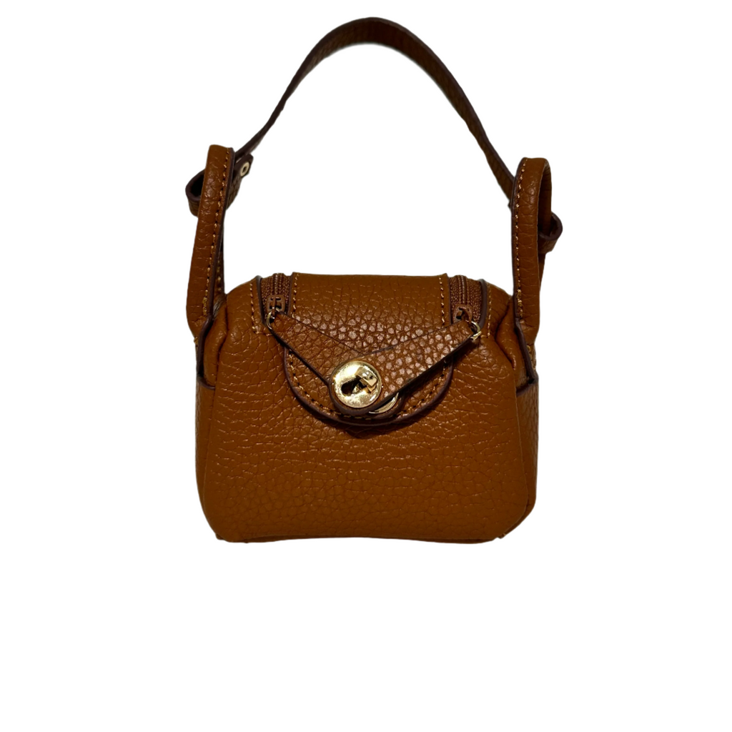 Brown mini crossbody leather bag charm with textured finish, featuring a gold-tone twist-lock closure and small shoulder strap. Stylish handbag or keychain accessory.