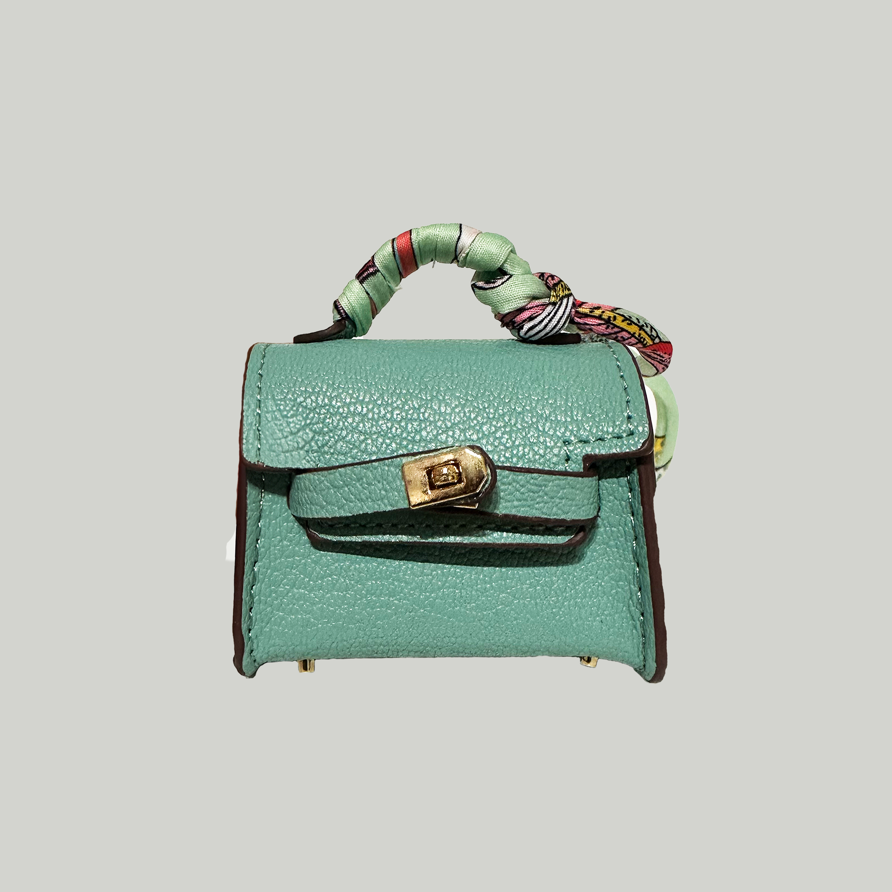 A designer inspired green mini handbag charm with a gold-tone lock and a blue and white striped strap.