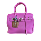 Pink handbag with a brown mini bag charm on a white background