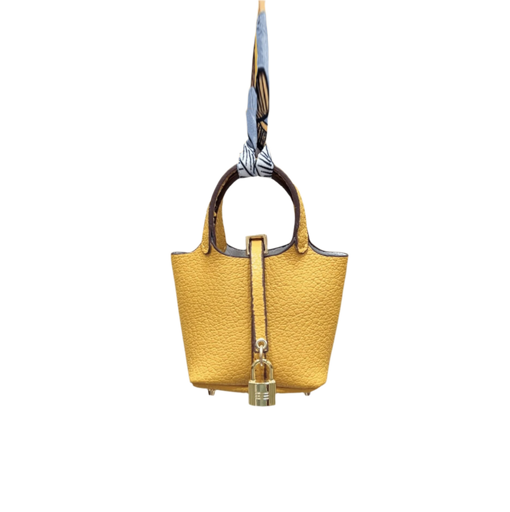 Yellow leather mini bucket bag charm with gold padlock detail, structured sides, and open-top storage functionality.