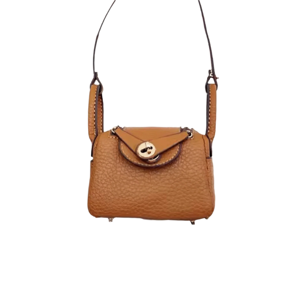 Brown textured leather mini crossbody bag charm with gold-tone twist-lock closure and thin shoulder strap. Keychain and handbag accessory.