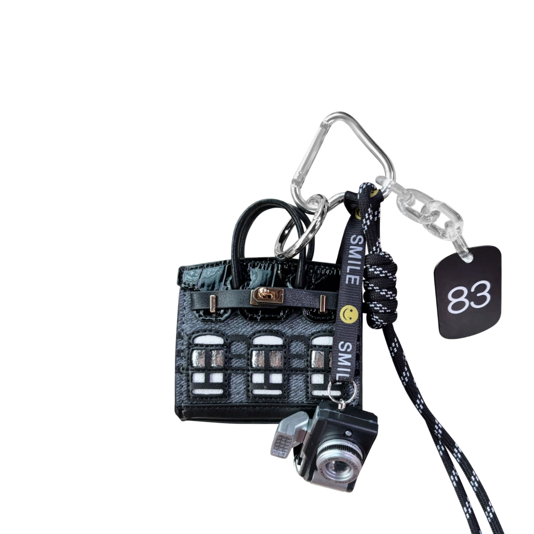 Black denim structured mini bag charm with defined top handle and trapezoid shape. Keyring and handbag accessory.