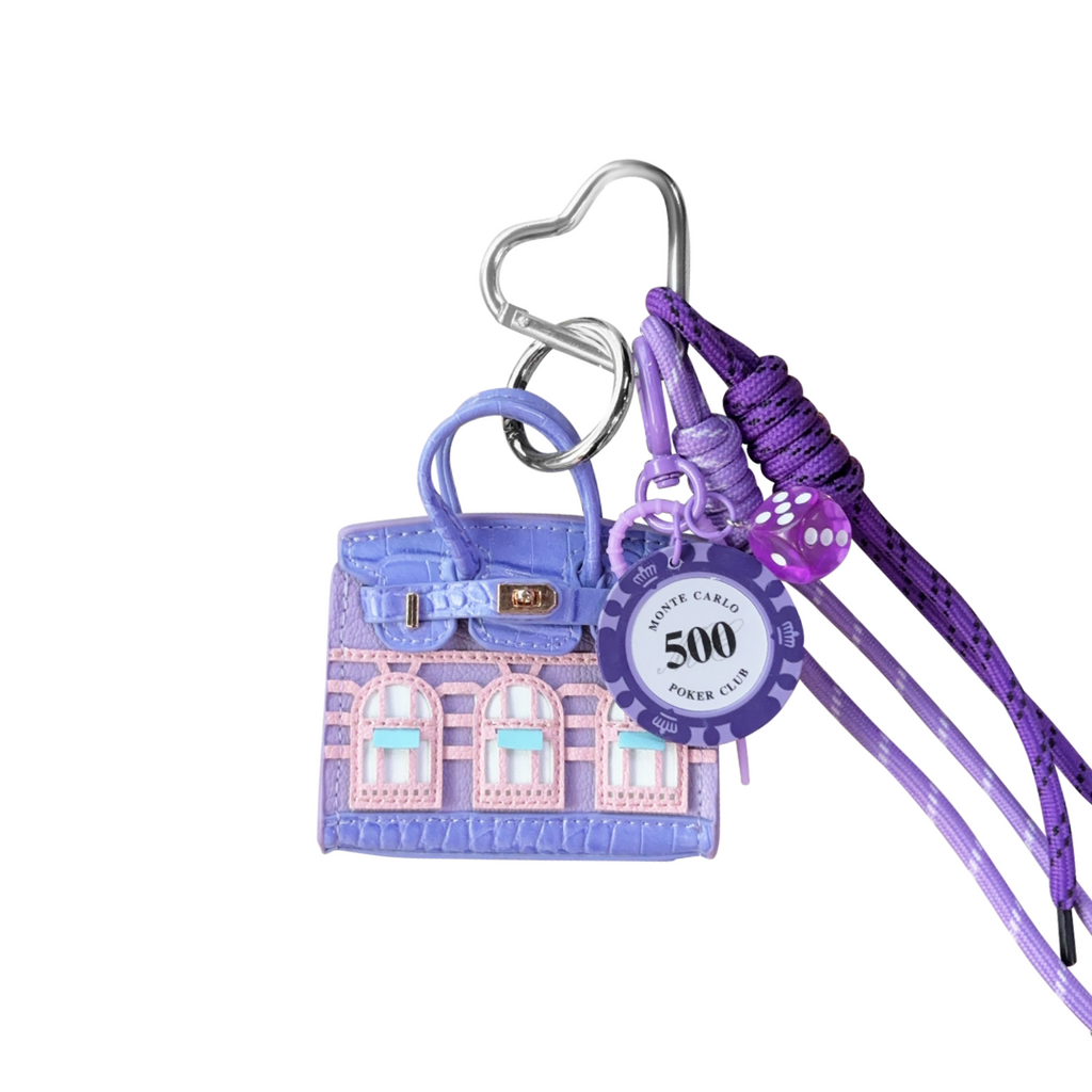 Lavender structured mini bag charm shaped like a house, featuring decorative window panels and a top handle.