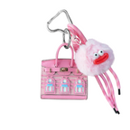 Pink structured mini bag charm shaped like a house, featuring decorative window panels and a top handle.