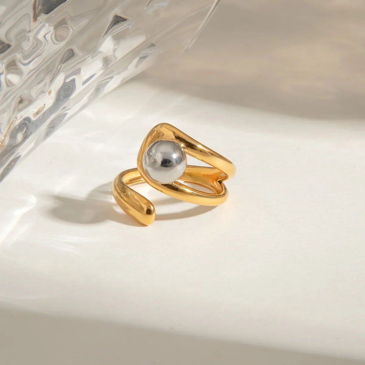 Gold ring with a pearl on a textured white surface