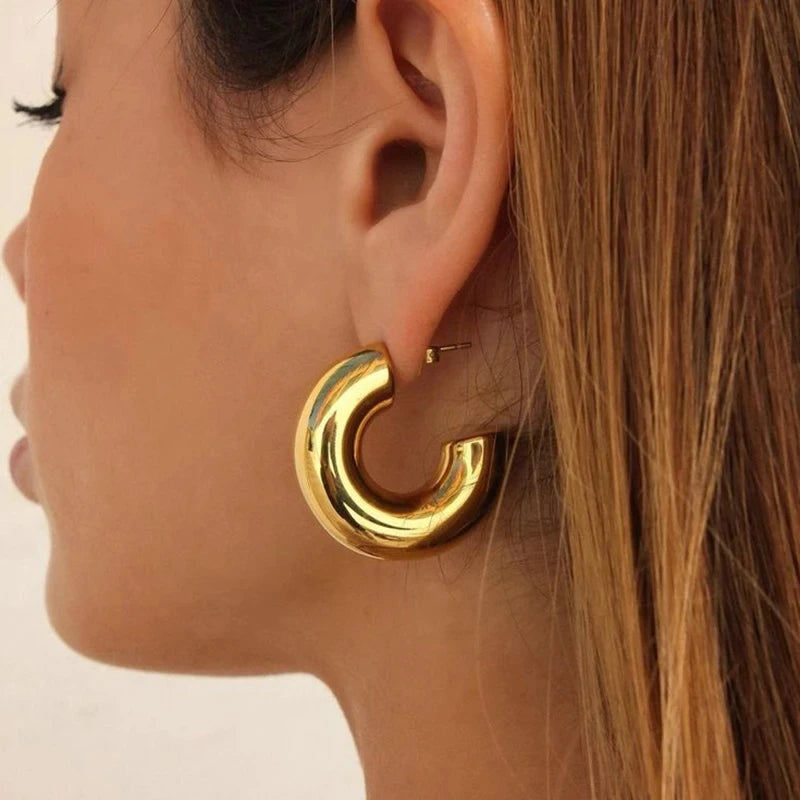 Gold hoop earring worn by a person with a neutral background