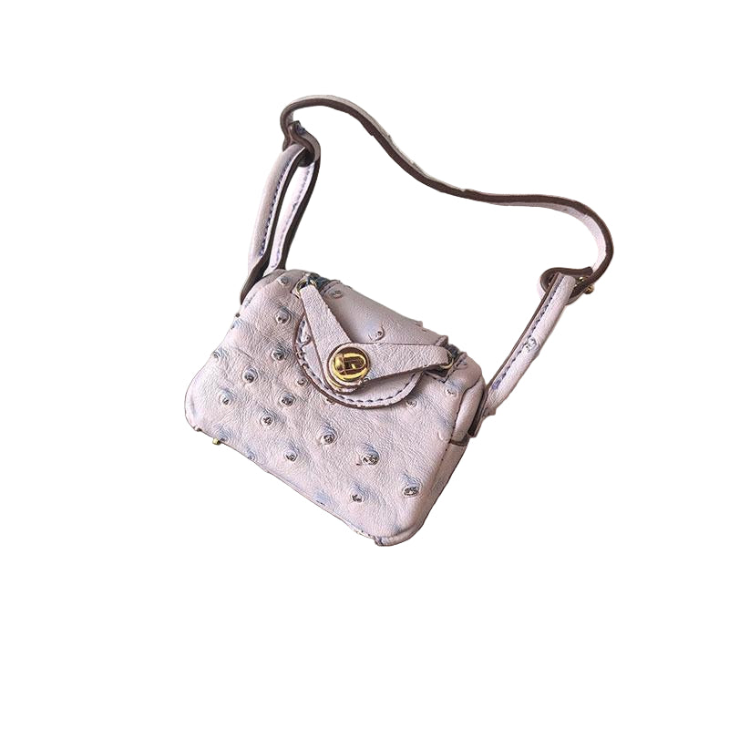 Pale pink Ostrich textured mini bag charm with flap closure and small shoulder strap.