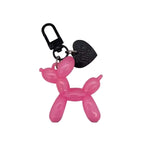 Pink balloon dog keychain with a black heart charm on a light gray background