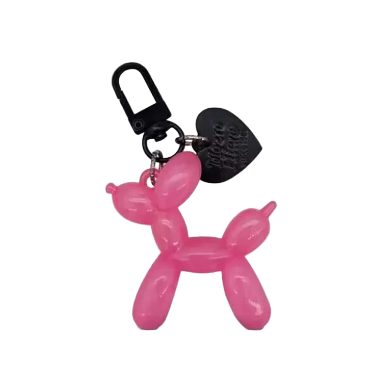 Pink balloon dog keychain with a black heart charm on a light gray background