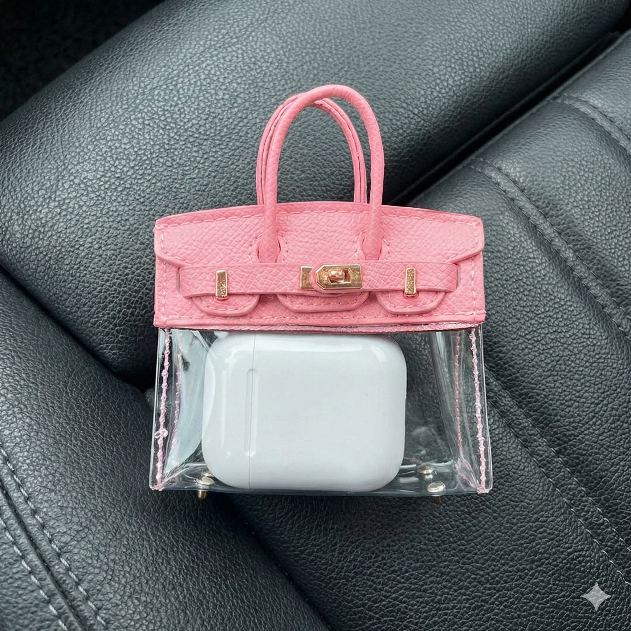 Pink handbag-shaped case with clear front holding a white device on a gray leather surface