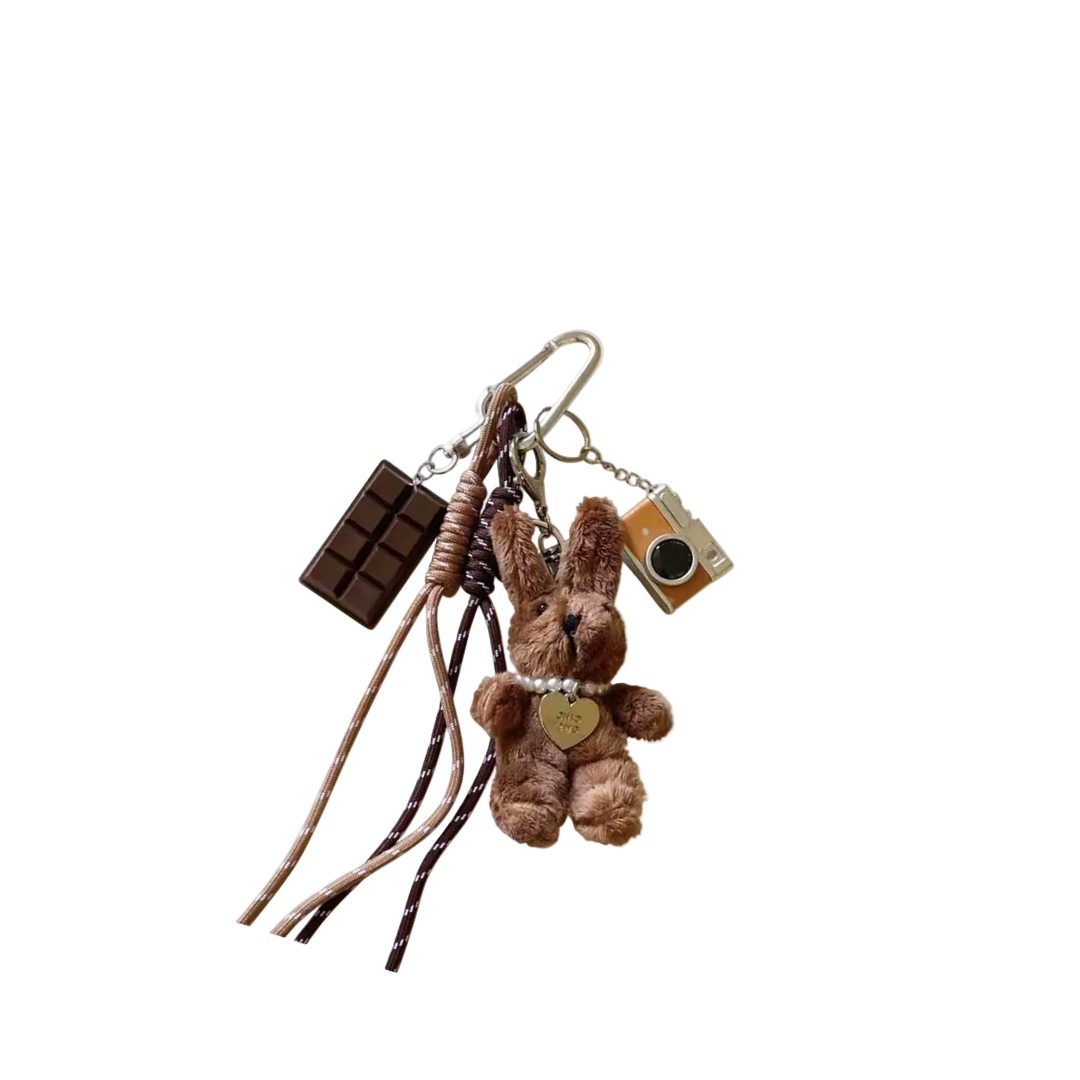Brown plush bunny bag charm with miniature chocolate bar and vintage camera components hanging from a keychain.