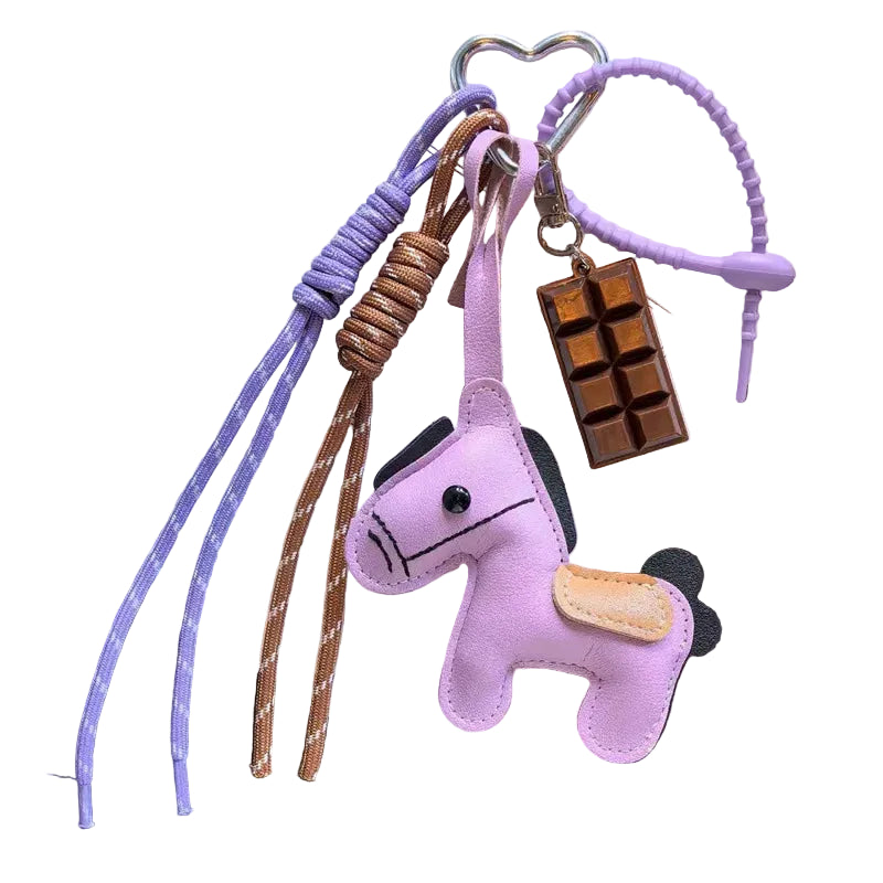 Purple horse-shaped keychain with a chocolate bar charm on a dark surface.