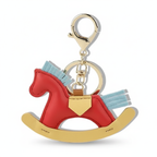 Red rocking horse keychain with gold accents on a white background