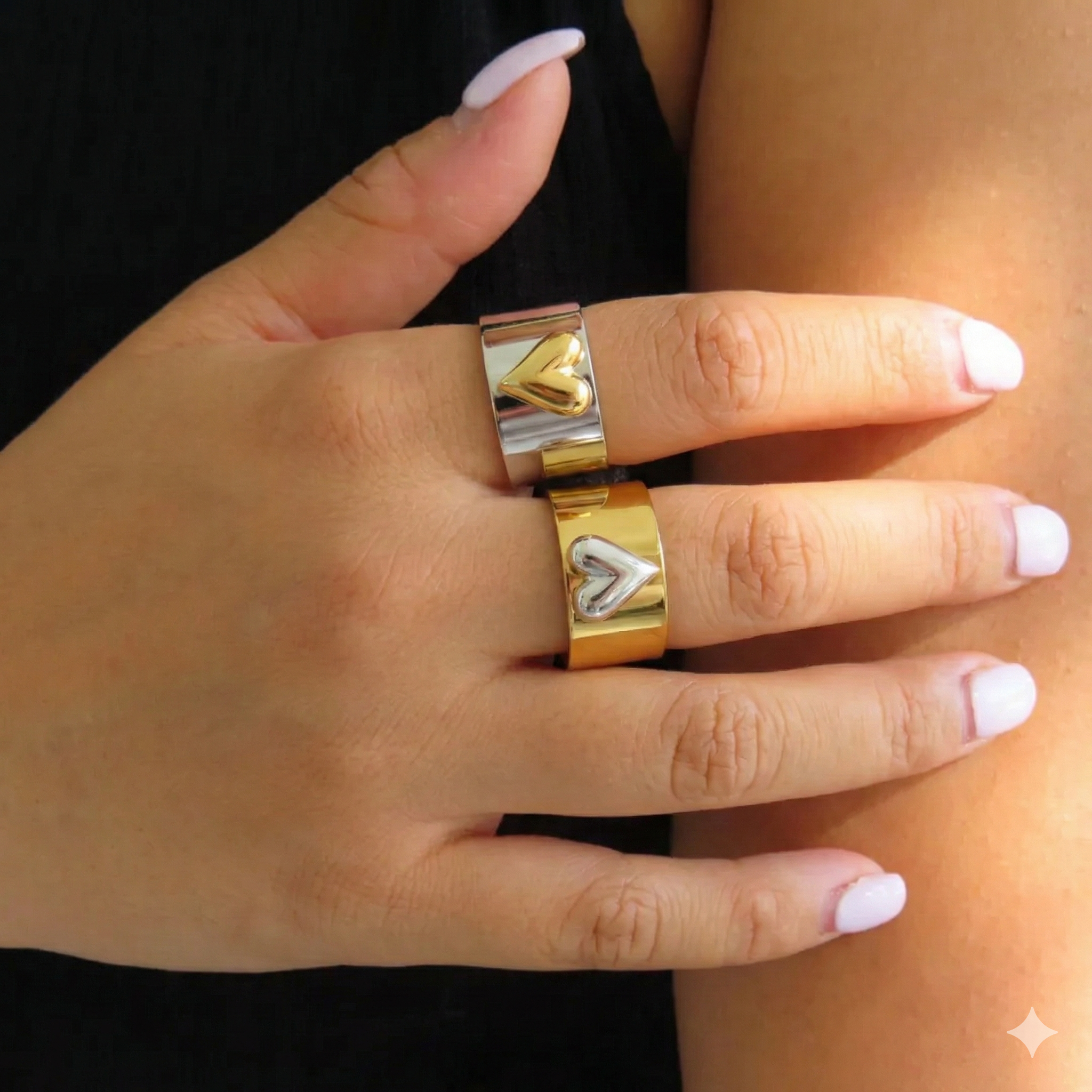 silver_and_gold_heart_mixed_metal on a horizontal hand with white painted fingernails on a blurred background