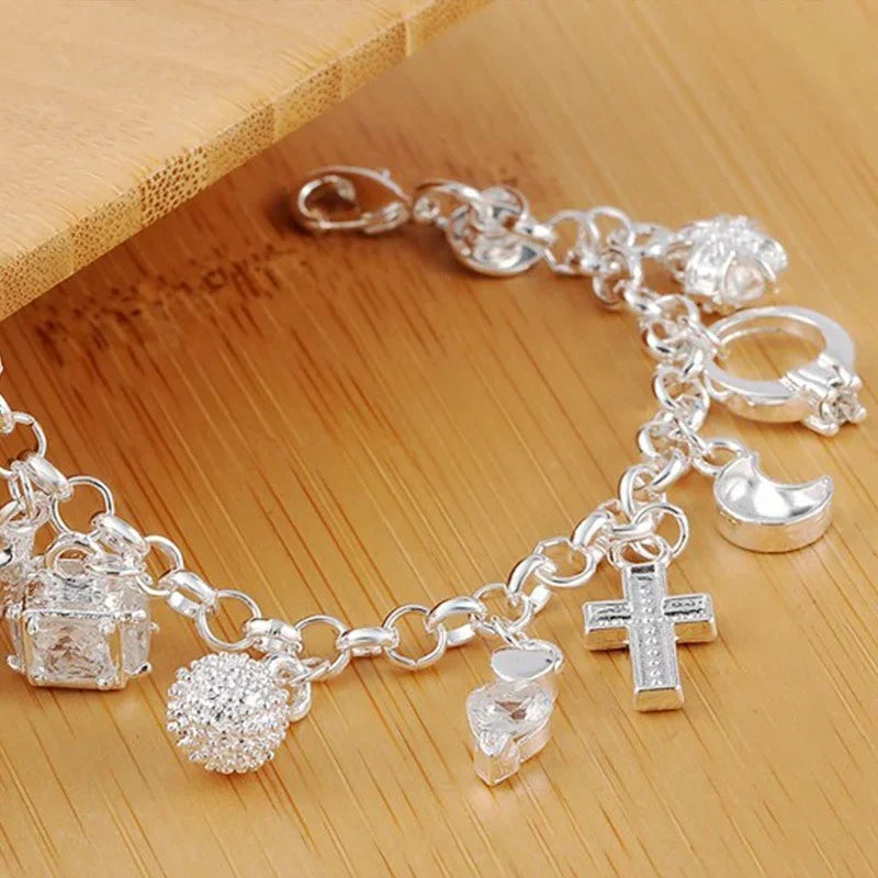 Silver charm bracelet with various charms on a wooden surface