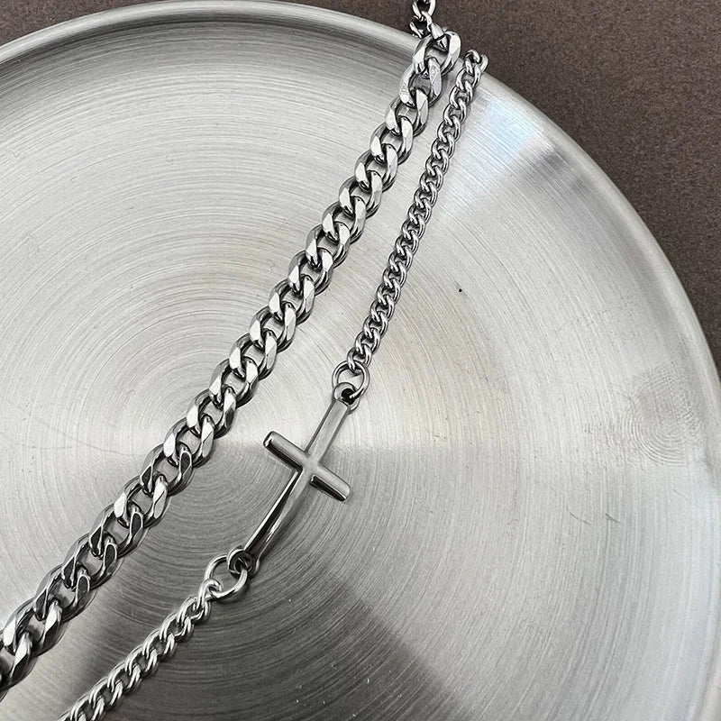Silver chain necklace with a cross pendant on a metallic surface