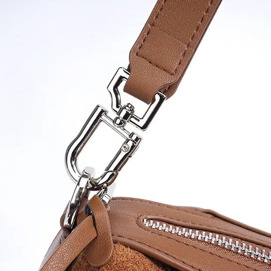 Close-up of a brown handbag with a silver clasp on a light gray background