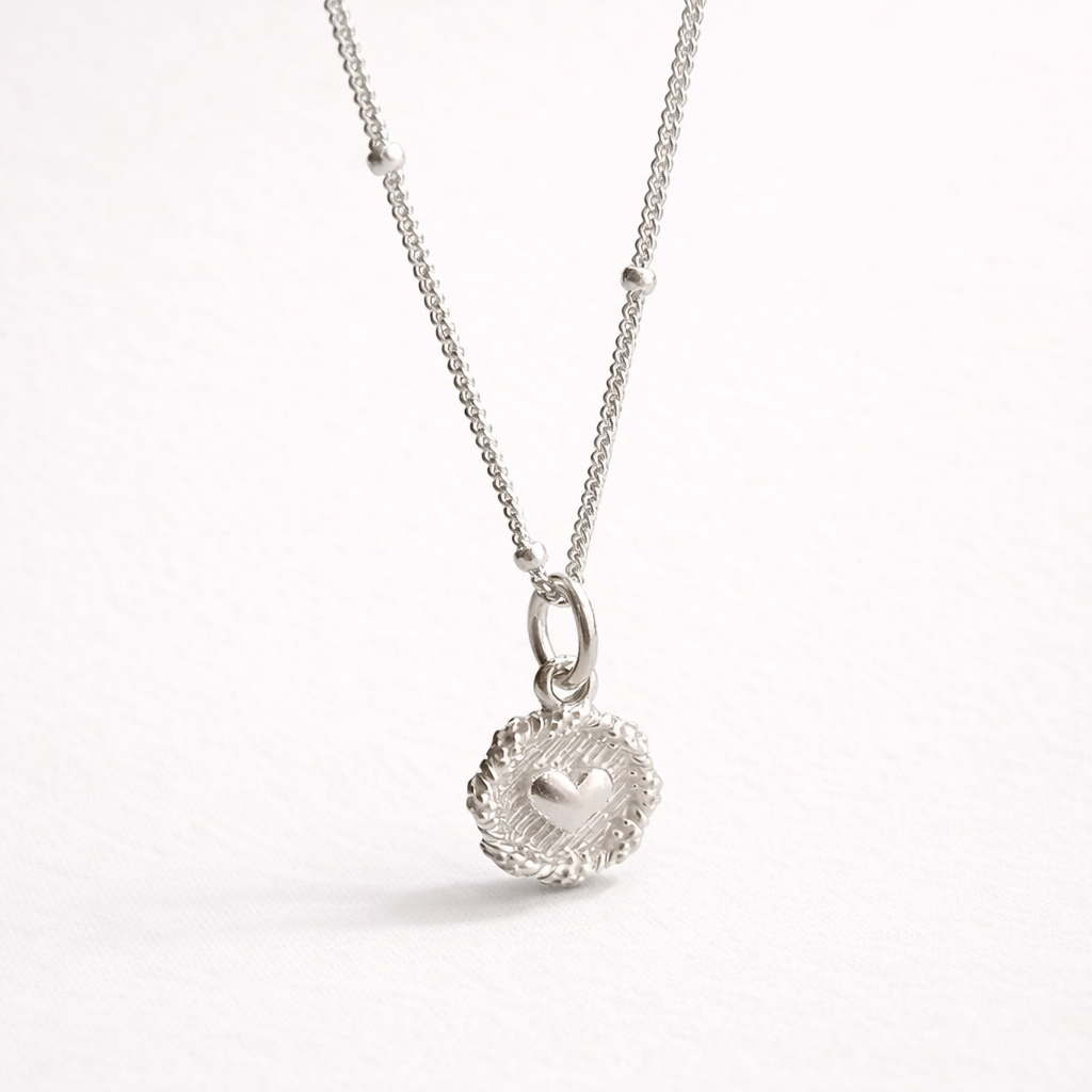 Silver necklace with a heart pendant on a white background