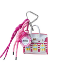 Magenta and white house-shaped keychain/mini bag charm with pink lanyard on a white background