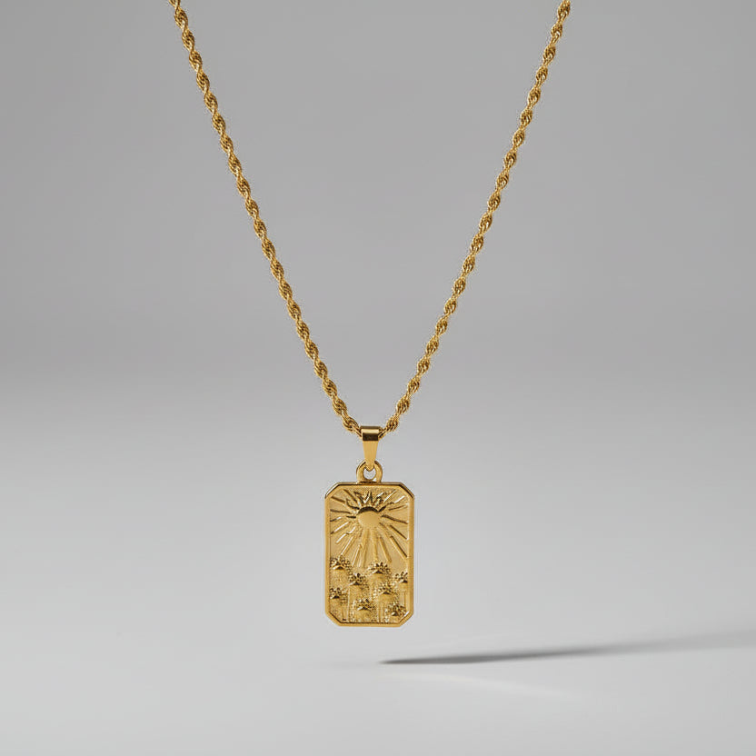 Gold pendant necklace on a light beige surface