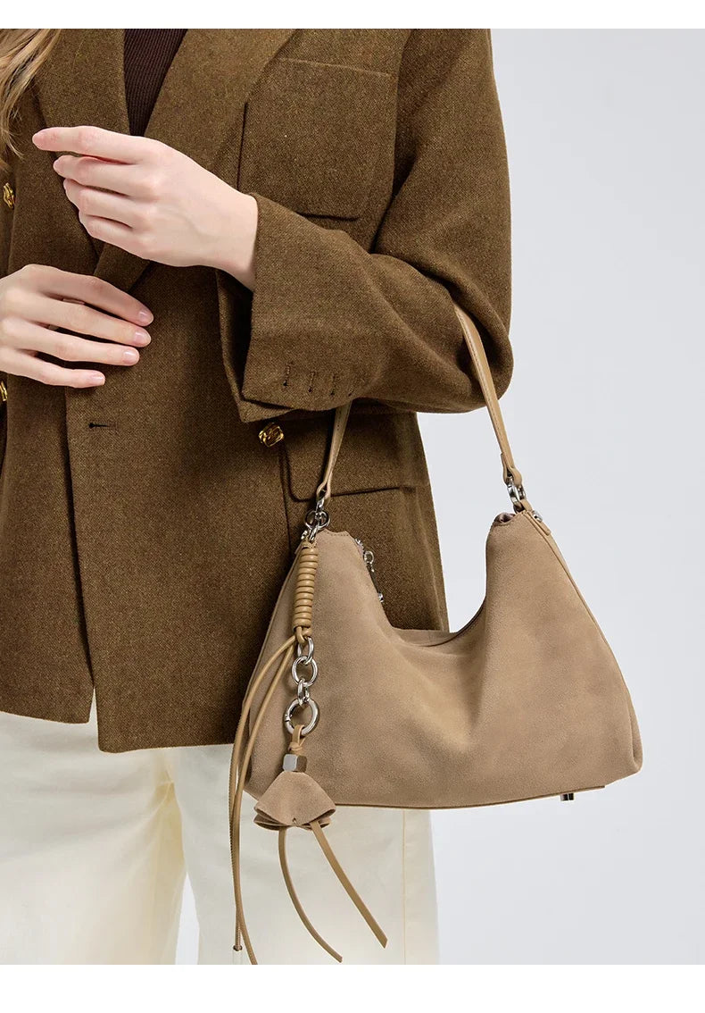 Person wearing a brown coat with a beige handbag on a light gray background