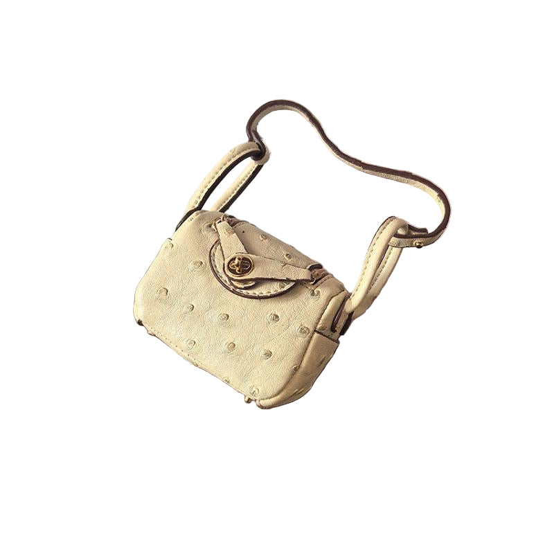 Light yellow textured mini bag charm with flap closure and small shoulder strap. Keychain and handbag accessory.