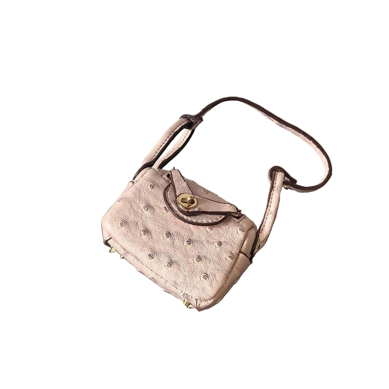Nude/Cream textured mini bag charm with flap closure and small shoulder strap. Keychain and handbag accessory.