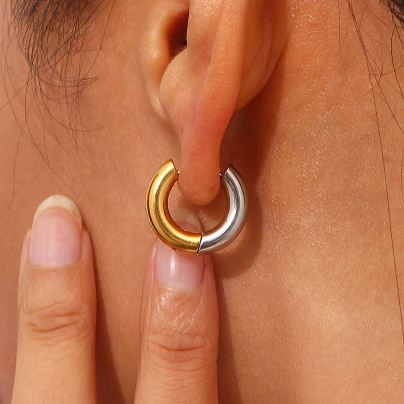 Close-up of a person wearing a gold and silver hoop earring.
