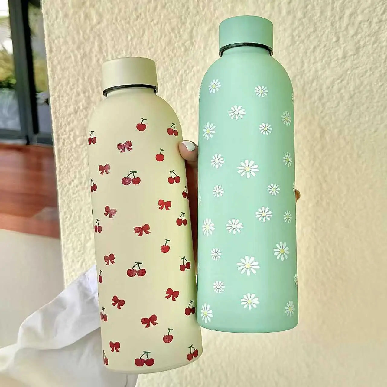Two patterned water bottles held against a neutral background