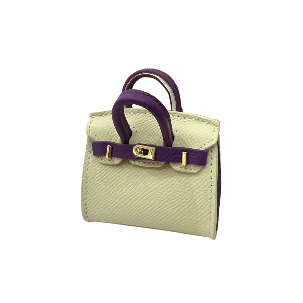 Creme and purple genuine leather structured bag charm with top handle, flap closure, securing straps, and gold-tone padlock hardware.