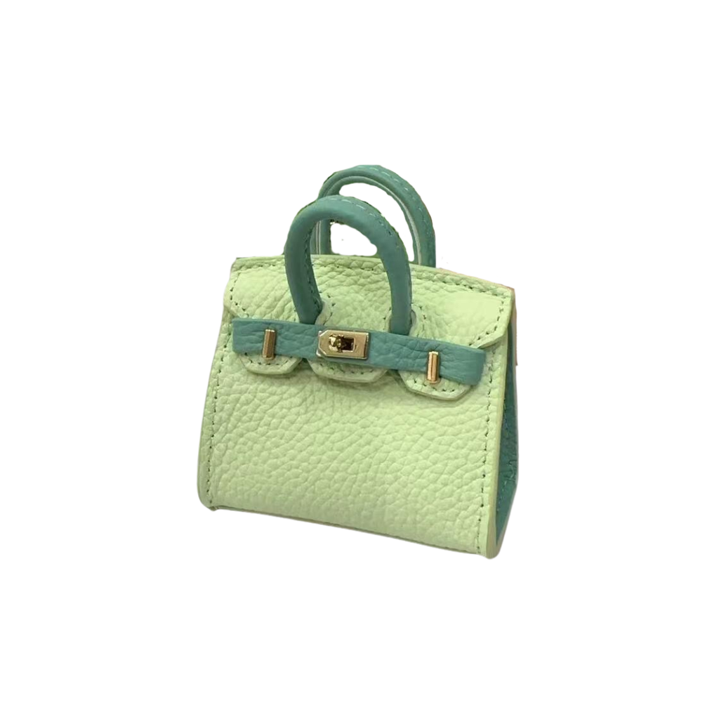 Green and light green genuine leather structured bag charm with top handle, flap closure, securing straps, and gold-tone padlock hardware.