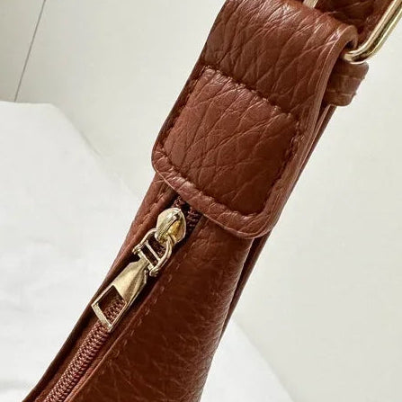 Brown leather bag with a smooth zipper on a white background