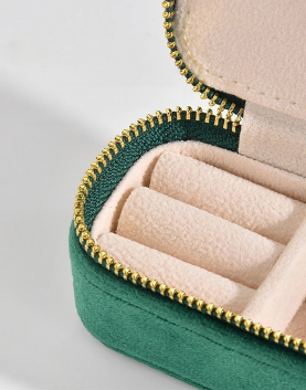 Green heart-shaped jewelry case with gold zipper on a light gray background